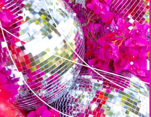 Disco balls laying on a bed of pink flowers